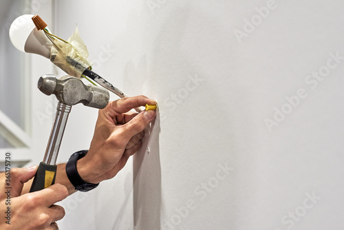 Obraz na plátně Close up of worker clogs a dowel into a wall using a hammer to install a new lam