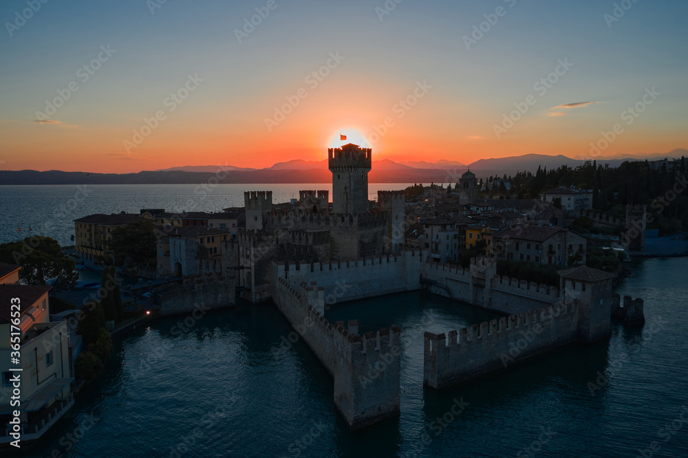 Castle Rocca Scaligera in Sirmione, Garda Lake. View by Drone. Sunset over the historical part of the city of Sirmione. Sun over the main tower of the castle