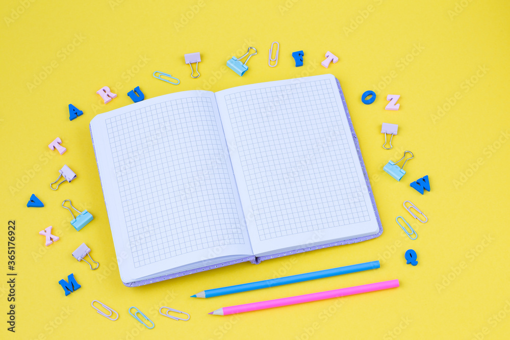 on a yellow background an open notebook, letters, pencils and paper clips on a yellow background an open notebook, letters, pencils and paper clips