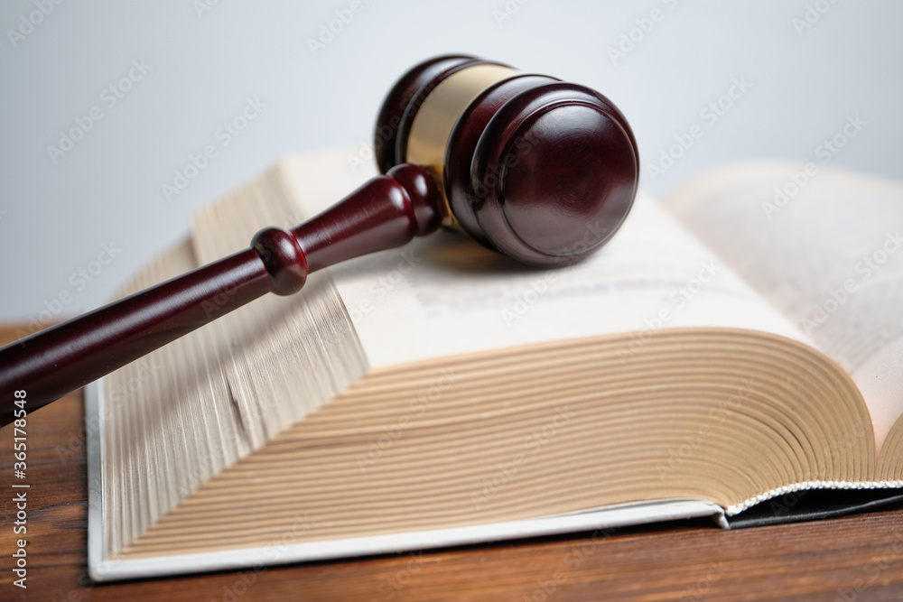 The judge hammer is next to the abstract book of the law. The judge hammer is next to the abstract book of the law.
