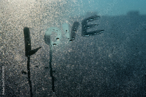Word "Love" written on foggy window background .The inscription on the sweaty glass. Attractive romantic message