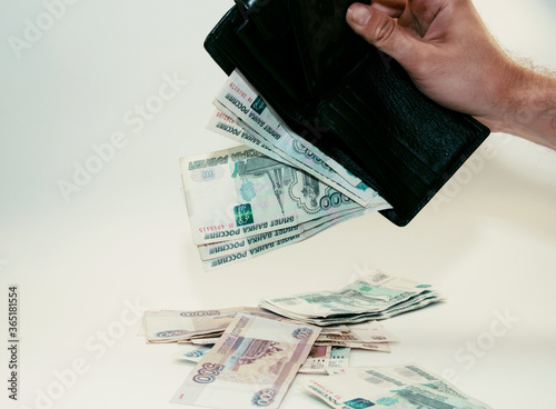 man pulls out paper bills from an upturned black wallet photo