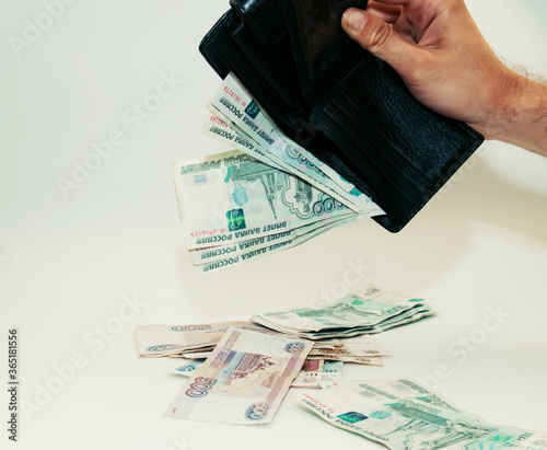 man pulls out paper bills from an upturned black wallet photo