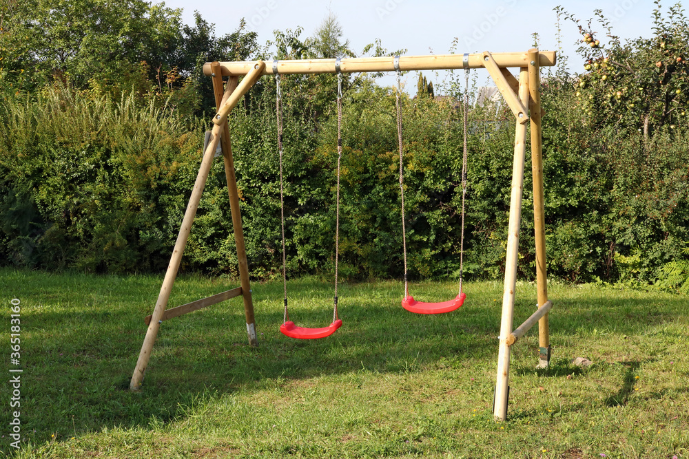 Children's swing made of logs and ropes and installed in the backyard of a rural house - obrazy, fototapety, plakaty 