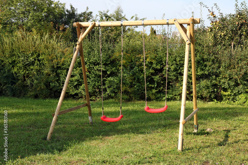 Children's swing made of logs and ropes and installed in the backyard of a rural house photo