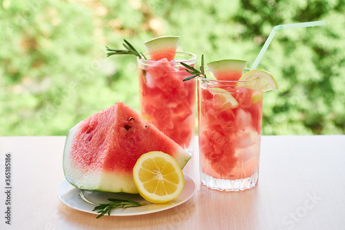 Summer refreshing drink with ice, slices of watermelon, lemon, rosemary,