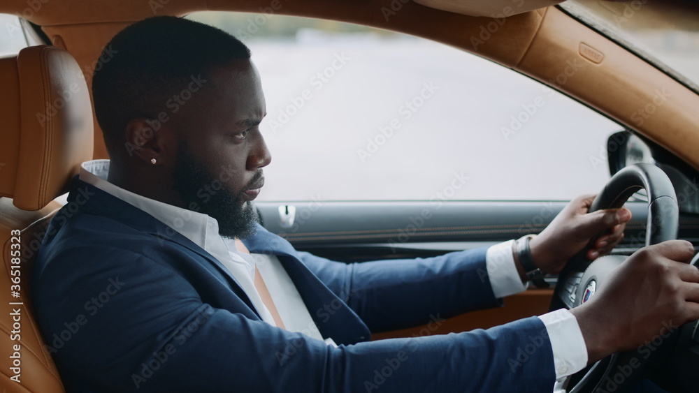 Side view of afro man driving alone at car. African man riding at modern vehicle