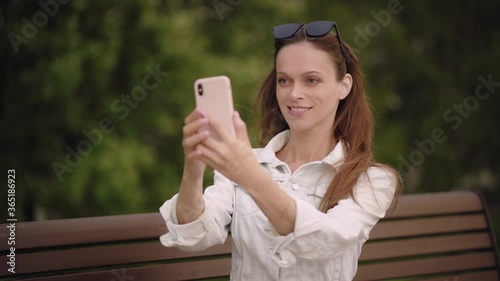 Pretty woman is taking selfie on her smartphone in the park