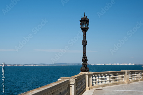 View of the promenade with white balusters and old street lamp looking out into the distance overlooking the ocean. Beautiful seascape, view from stone balustrade on sunny summer day. 