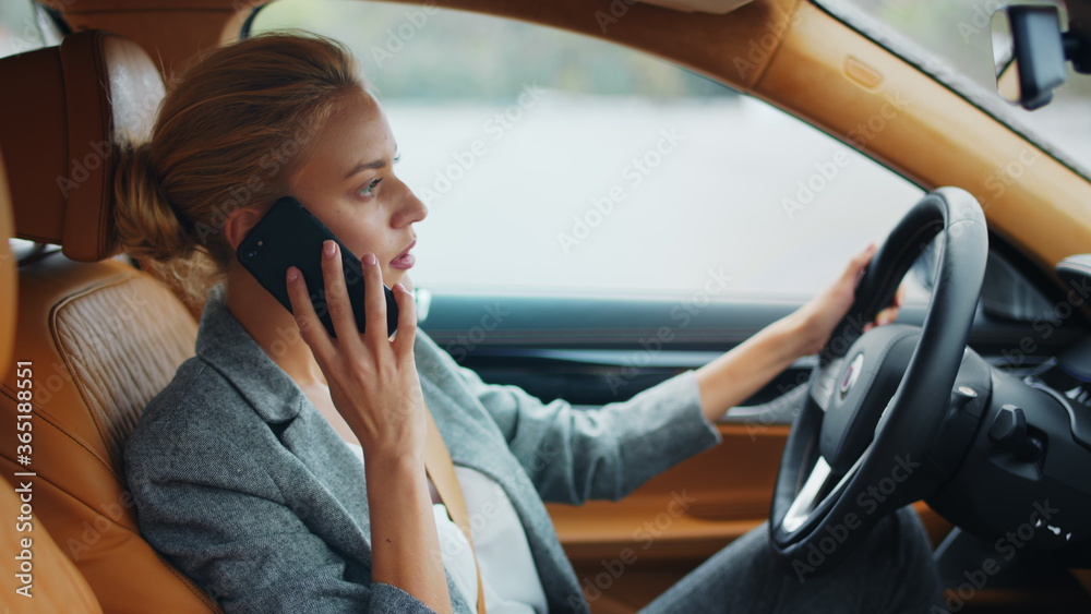 Business woman talking phone behind steering wheel. Female executive using phone