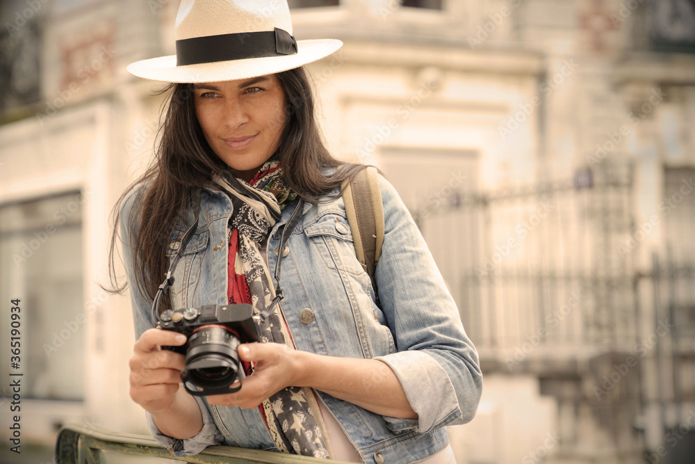 Woman wearing hat, taking pictures in european town during vacation