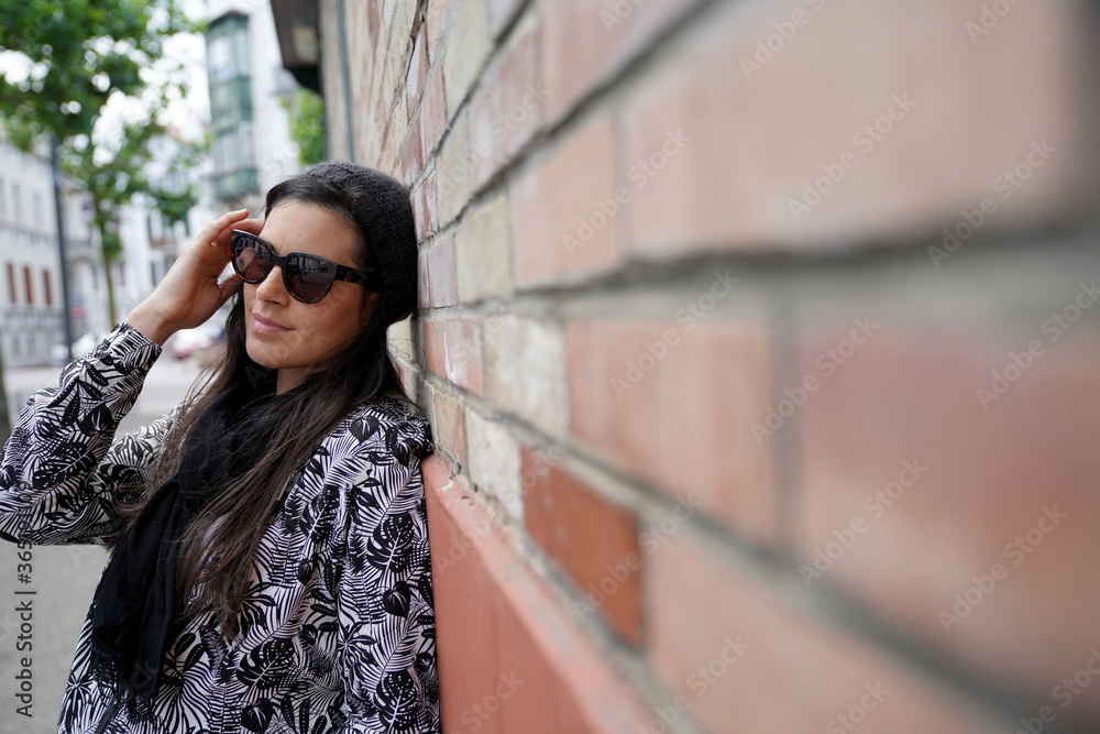 Fototapeta premium Trendy woman standing on brick wall in town