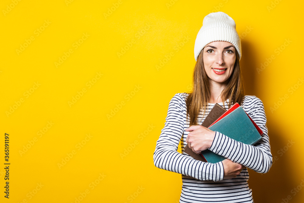 Beautiful young smiling girl holds books on a yellow background. Beautiful young smiling girl holds books on a yellow background.