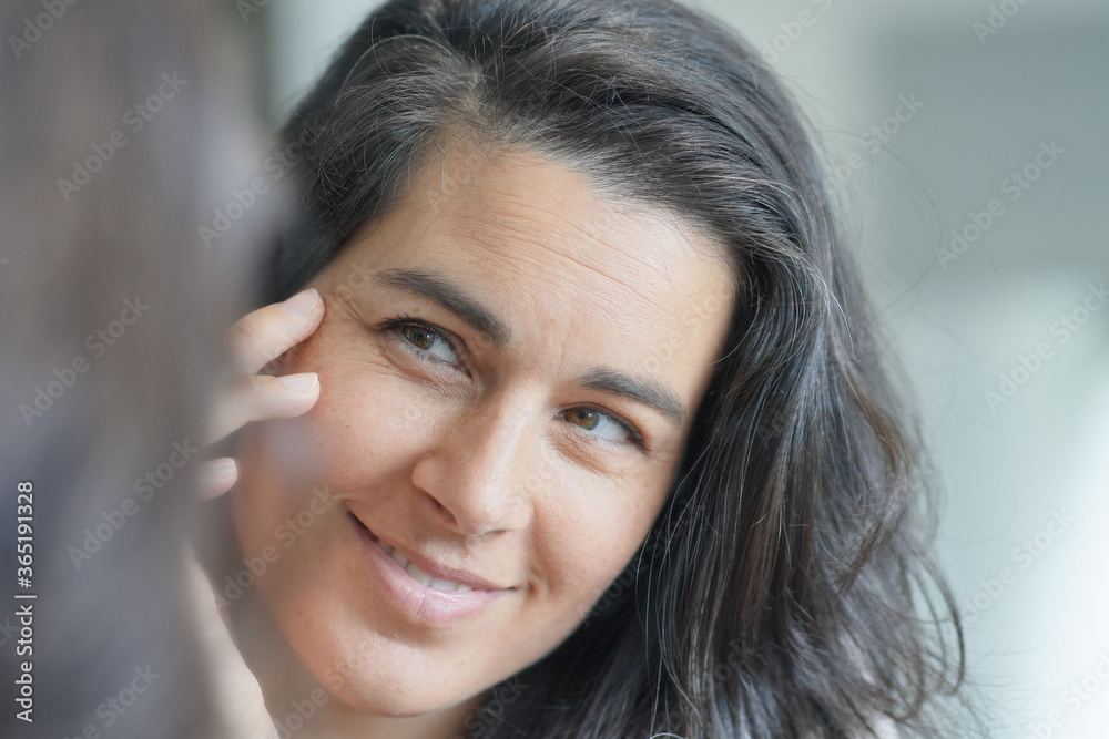 Naklejka premium Portrait of beautiful woman with dark hair, looking in the mirror