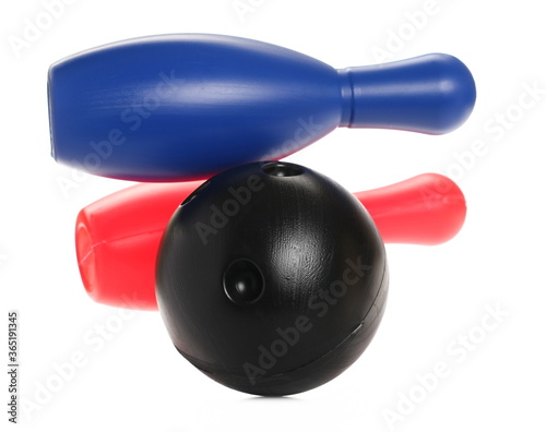 Black bowling ball striking colorful pins, skittles in air isolated on white background