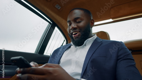 African businessman looking smartphone at car. Afro man holding phone at vehicle