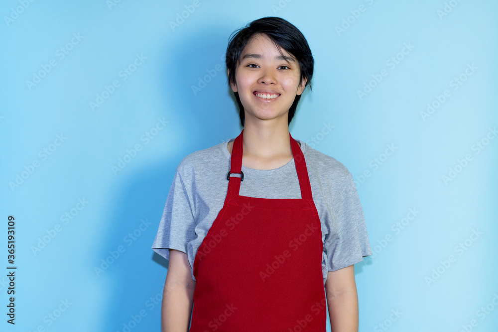 Laughing young asian male waiter with red apron Laughing young asian male waiter with red apron
