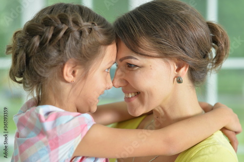 Portrait of a charming little girl hugging with mom at home