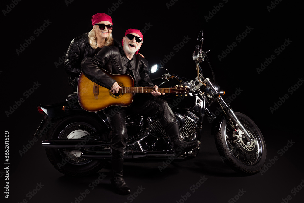 Photo of aged bikers man lady couple sit chopper moto feel young rock bike festival meeting play sing guitar band wear trendy rocker leather jacket pants isolated black color background