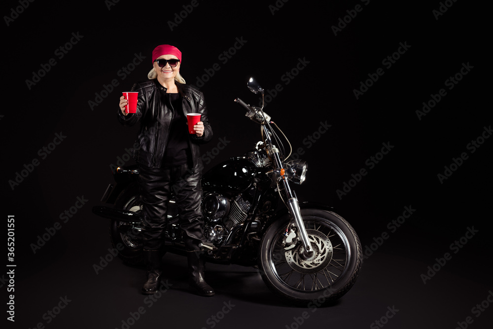 Full length body size view of her she nice attractive cheery grey-haired lady hipster rocker chopper rider wearing leather clothes inviting you drink beer party leisure isolated black color background