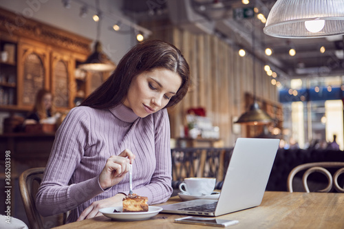 Woman works remotely online from cafe while quarantine coronavirus is in effect. Concept of checking mail, blogger, freelancer