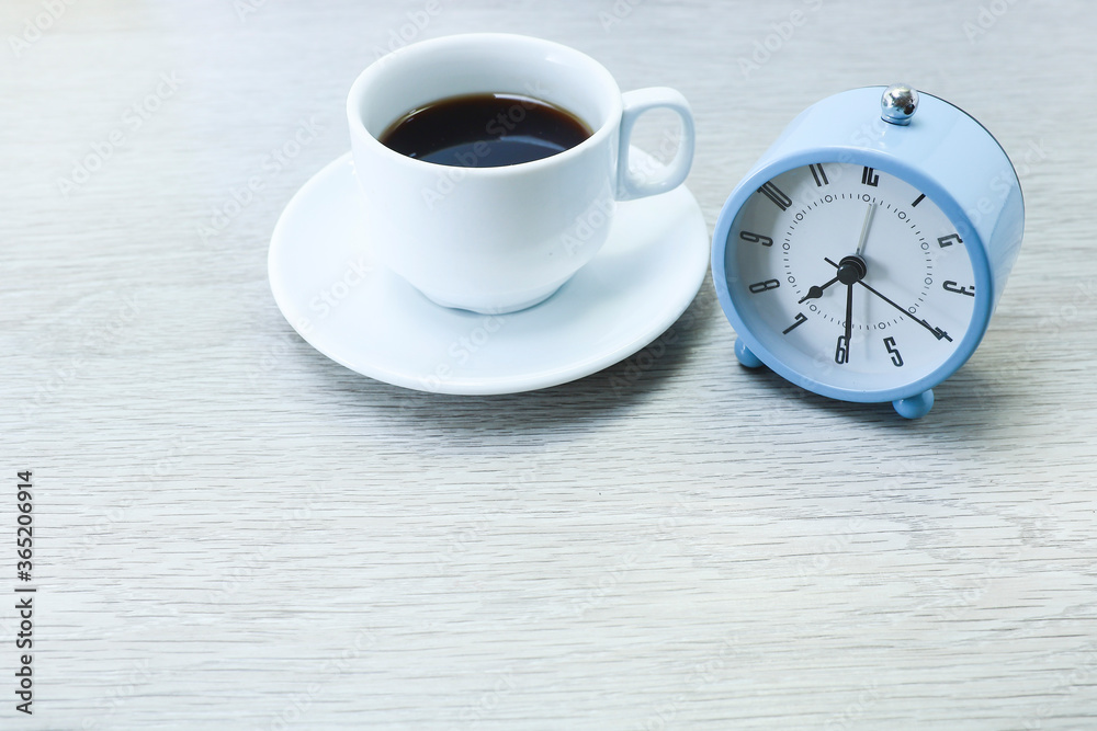Alarm clock and a cup of coffee on wooden table Alarm clock and a cup of coffee on wooden table