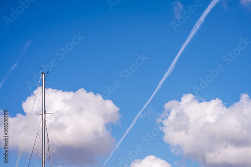 Blue sky the cloud mast and airplane contrail
