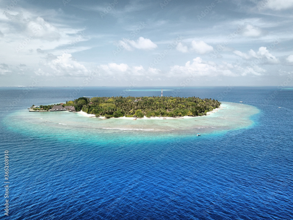 Maldives: Tropical Desert Island from Above, with White Sand Beach, Palm Trees, Turquoise Sea, Blue Sky and Dramatic Clouds (Bandos Maldives, North Male Atoll, Indian Ocean) DJI Mavic Pro Drone