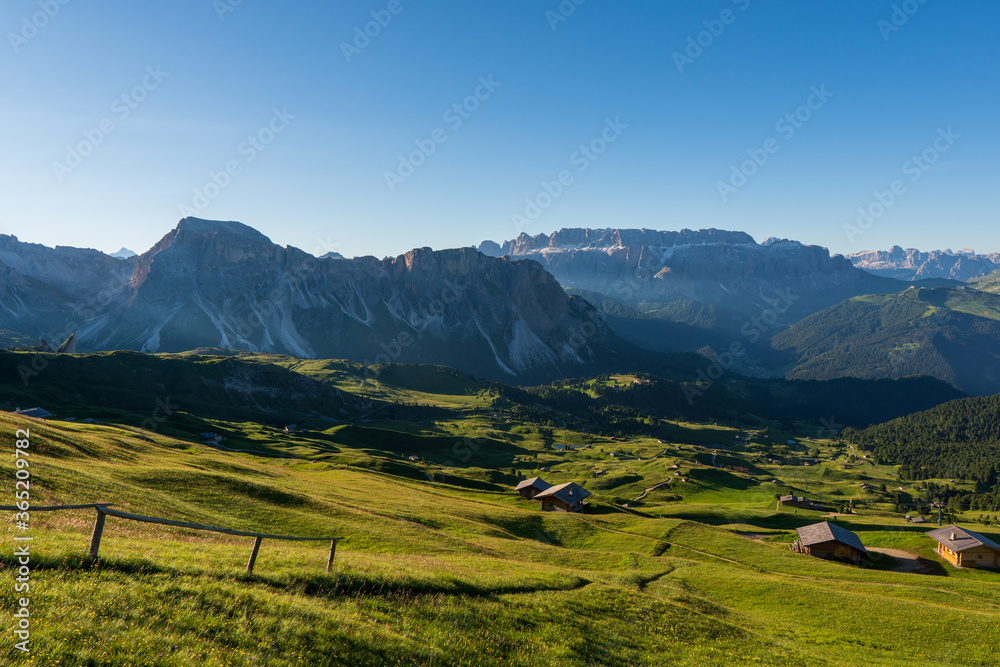Seceda mountain with blue grass and wooden cottages on foreground. Italy beauties