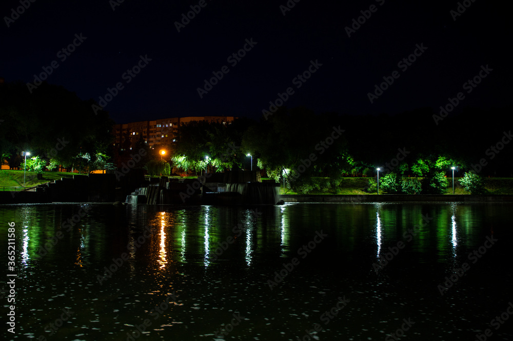 Night city park with a river and beautiful lanterns in summer