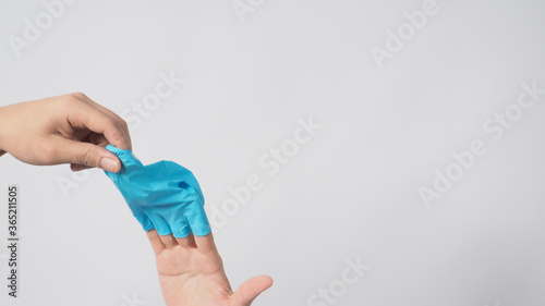 Left hand is pulling right hand with blue latex gloves on white background.