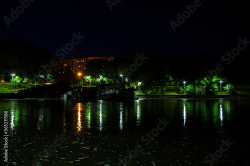 Night city park with a river and beautiful lanterns in summer © Payllik