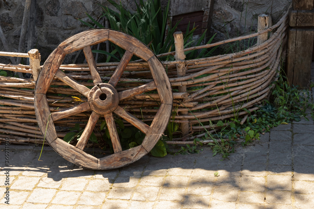 old wooden wheel near the fence.Detail of vehicle. Rural background of country life. Natural concept