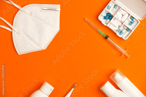 Covid-19 (coronavirus) concept with medical instruments and protective material, orange background, top view, central space for text.