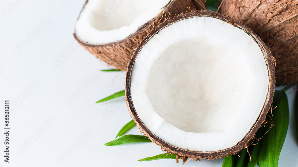 Ripe half cut coconut with green leaves on a white background. Isolated concept. Ripe half cut coconut with green leaves on a white background. Isolated concept.
