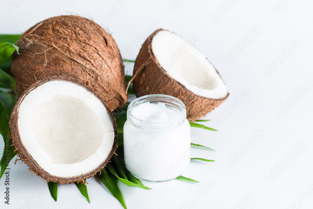Ripe half cut coconut and cream with green leaves on a white isolated background. Healthcare and medical concept. Skin care.
