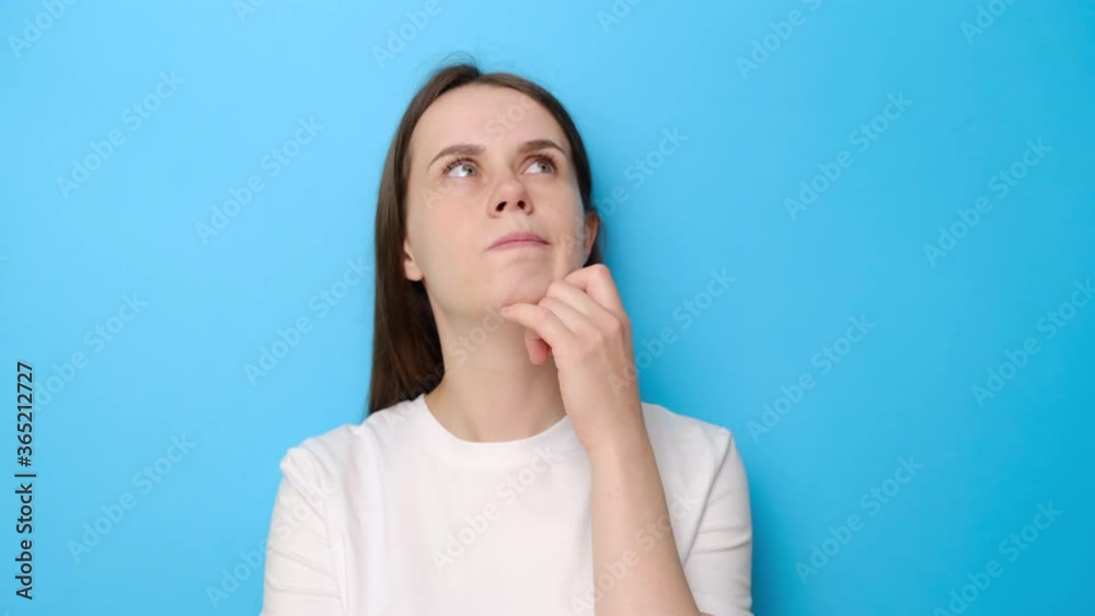 Pensive young woman leaning hand, while thinking over difficult choice, imagining plan in mind, dressed in white t-shirt, pondering idea looking puzzled clueless, isolated on blue studio background Pensive young woman leaning hand, while thinking over difficult choice, imagining plan in mind, dressed in white t-shirt, pondering idea looking puzzled clueless, isolated on blue studio background
