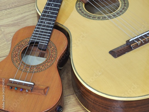 An acoustic guitar and two Brazilian musical instruments: cavaquinho and pandeiro (tambourine), on a wooden surface. They are widely used to accompany samba and choro, two  Brazilian rhythms. Top view photo