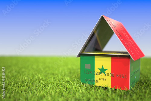 National flag of Senegal on bank card house in the grass. Home loans related 3D rendering