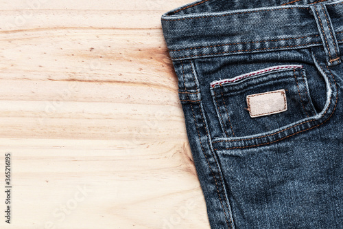 close up of blue jeans pocket with wooden background