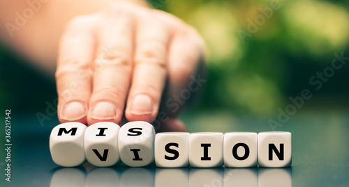 From a vision to a mission. Hand turns dice and changes the word vision to mission. photo