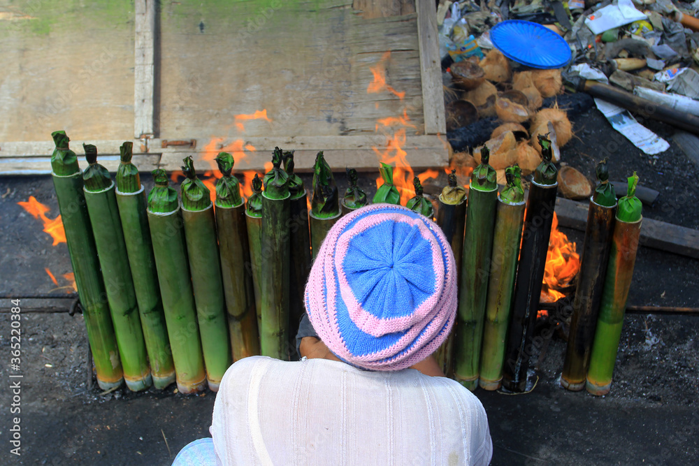 Fototapeta premium The process of making lemang in Pekanbaru, Riau, Indonesia. Lemang is a food made from glutinous rice which is put into bamboo and given coconut milk and other spices and then burned until cooked.