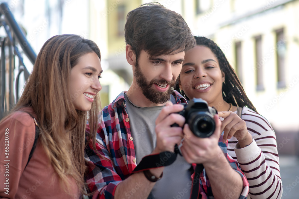 Guy and two girls looking at photos in the camera Guy and two girls looking at photos in the camera