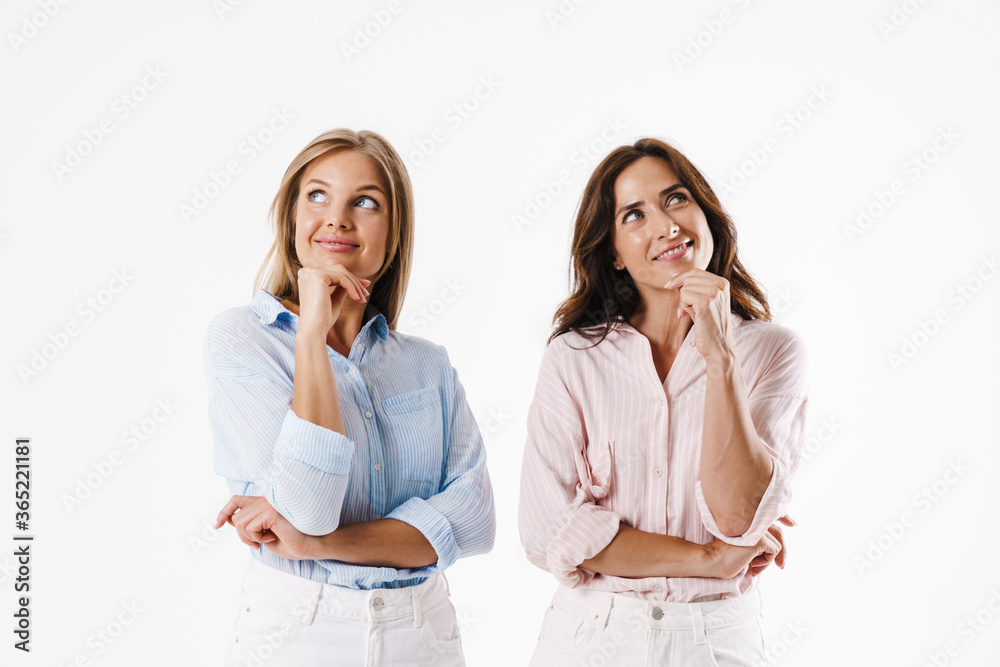Image of smiling two women looking upward while posing at camera Image of smiling two women looking upward while posing at camera