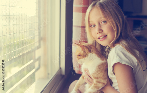 Portrait of a cute 9 years old girl with lovely red cat. Smiles and happiness