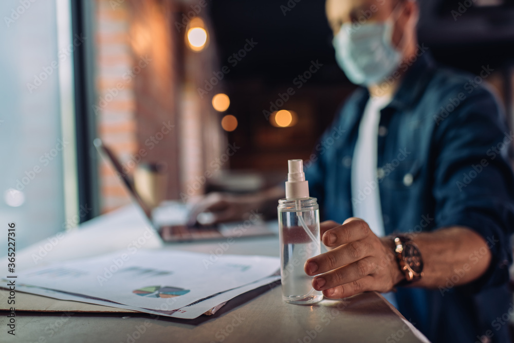 selective focus of businessman in medical mask touching bottle with sanitizer near charts and graphs selective focus of businessman in medical mask touching bottle with sanitizer near charts and graphs