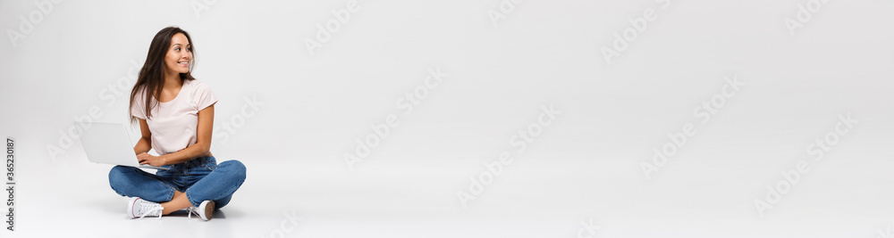 Photo of young smiling woman in casual wear, holding laptop, loo Photo of young smiling woman in casual wear, holding laptop, loo