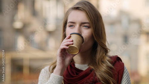 Smiling girl face drinking coffee outdoors. Pretty woman sipping hot drink.