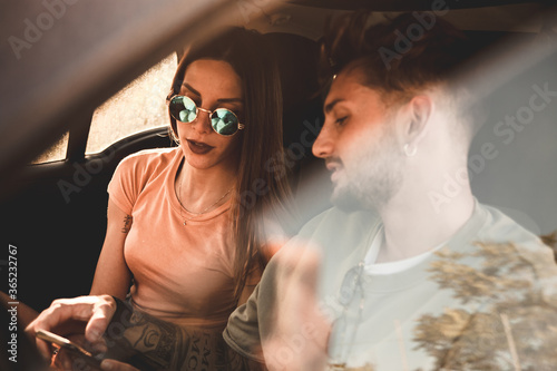 Momento di relax con il telefono di una giovane coppia di fidanzati nella loro auto mentre sono in viaggio per le vacanze estive photo