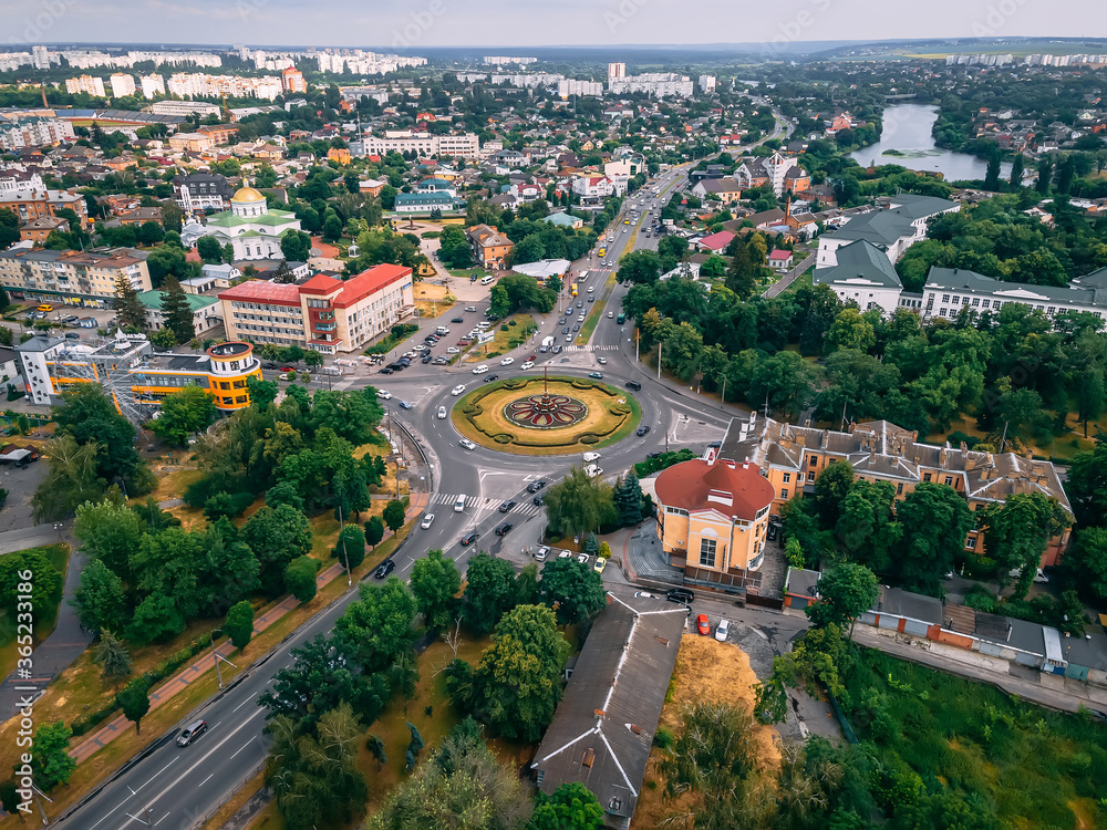 Aerial view of roundabout road with circular cars in small european city at summer afternoon